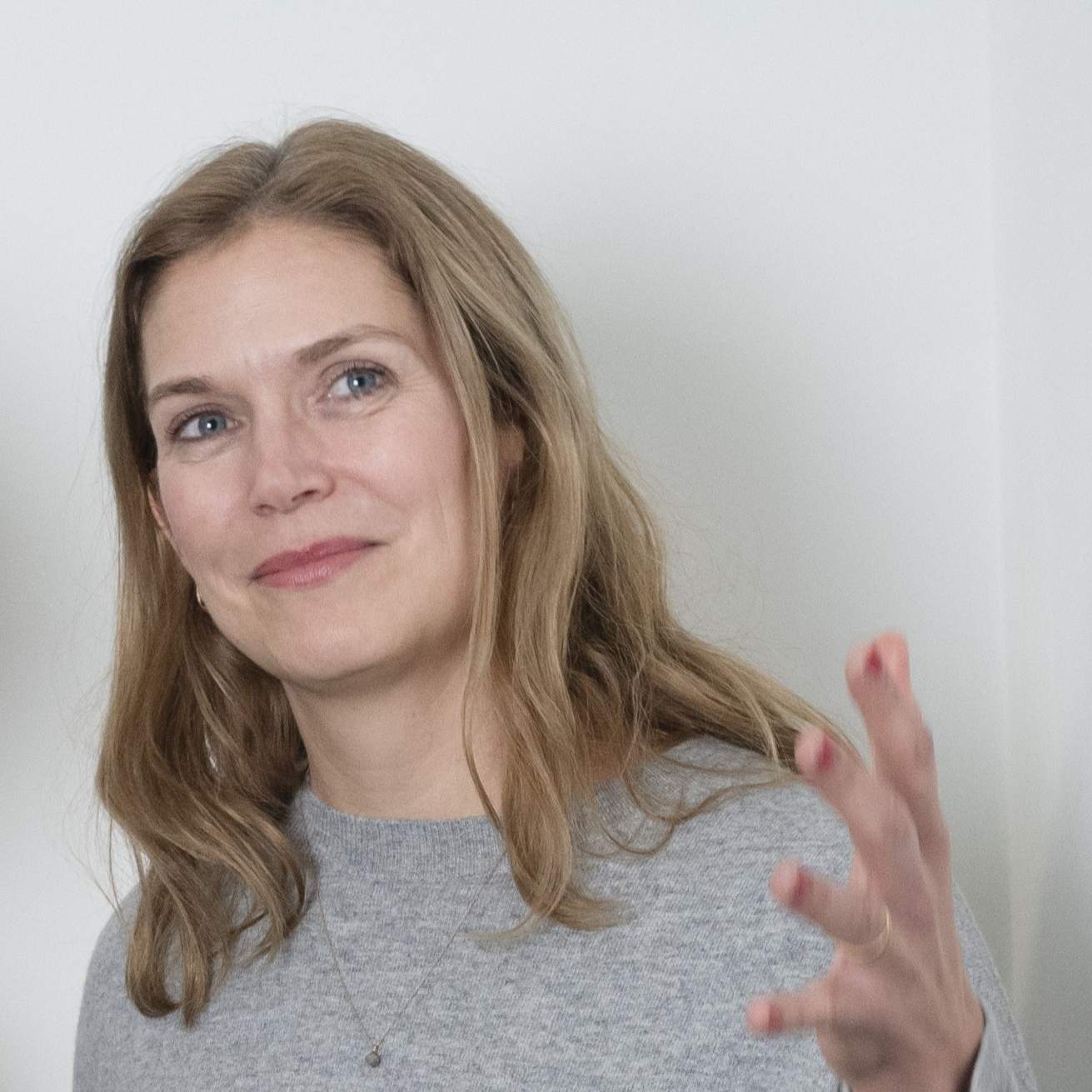 KI generiert: Das Bild zeigt eine Frau mit langen, braunen Haaren, die sich mit der Hand über den Mund fährt und dabei direkt in die Kamera blickt.