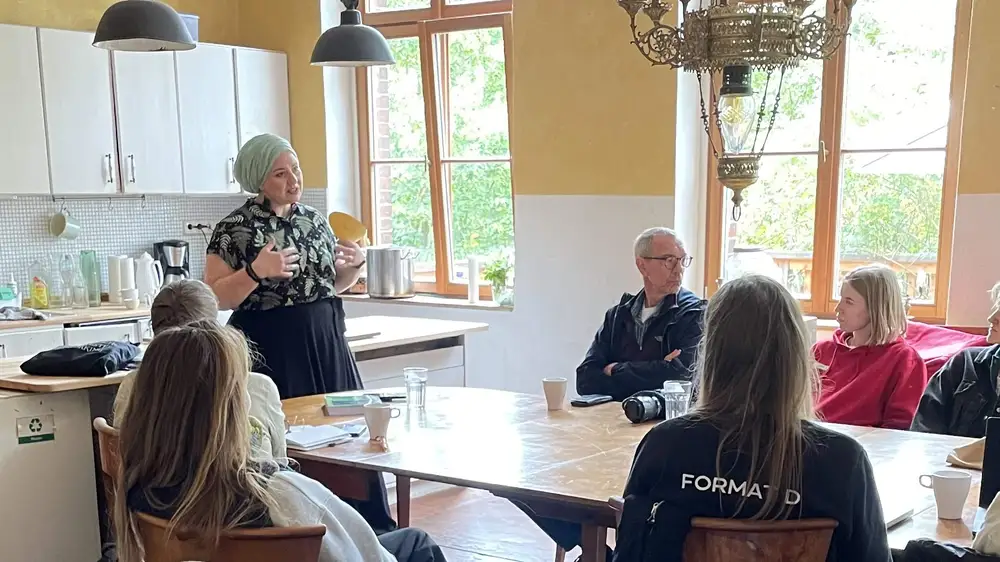 KI generiert: Das Bild zeigt eine Gruppe von Menschen, die in einem hellen, modernen Café sitzen und sich unterhalten, während sie Getränke genießen.